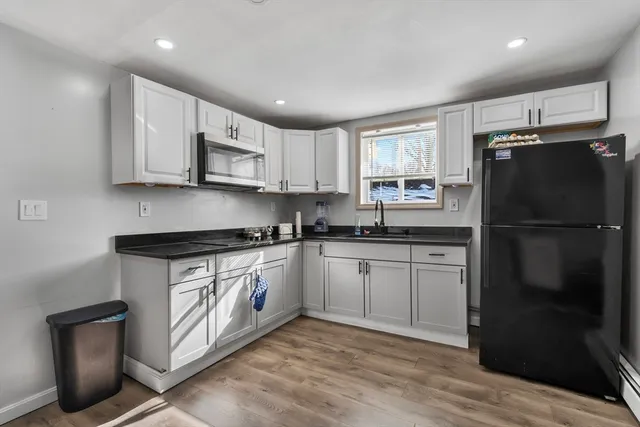 a kitchen with stainless steel appliances granite countertop a refrigerator sink and white cabinets