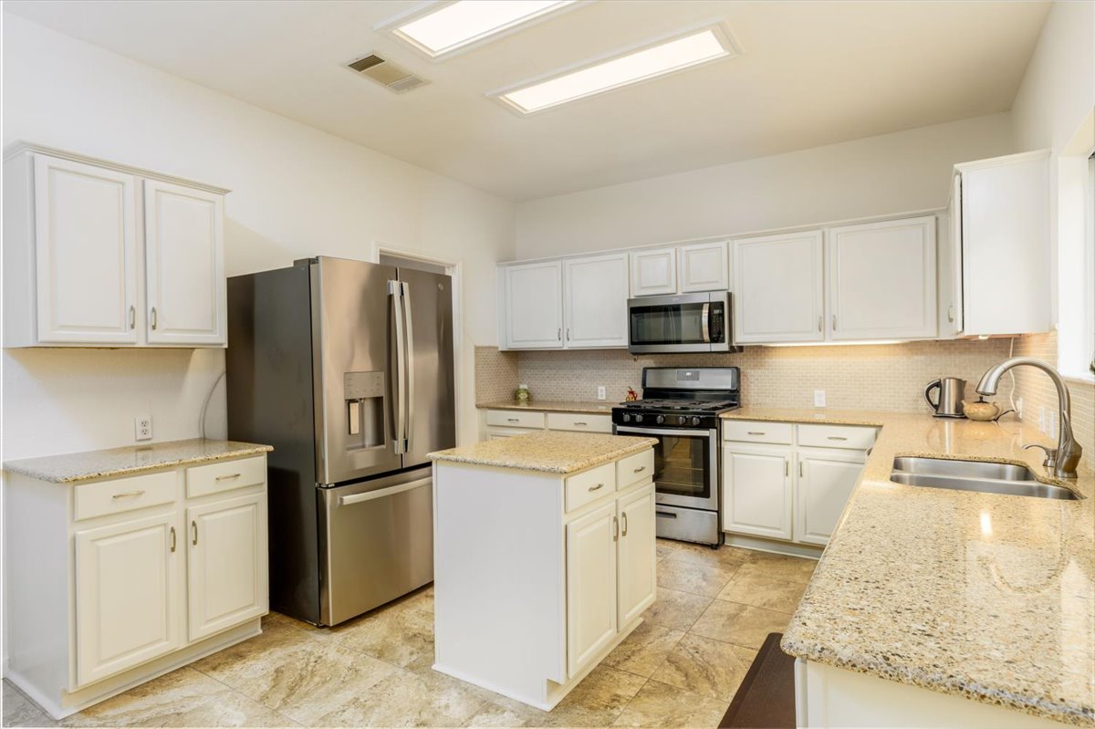 7136 Ridge Oak Road Austin, TX 78749 - Photo 11 of 28 A functional kitchen features an island, ample cabinetry, and sleek stainless steel appliances.