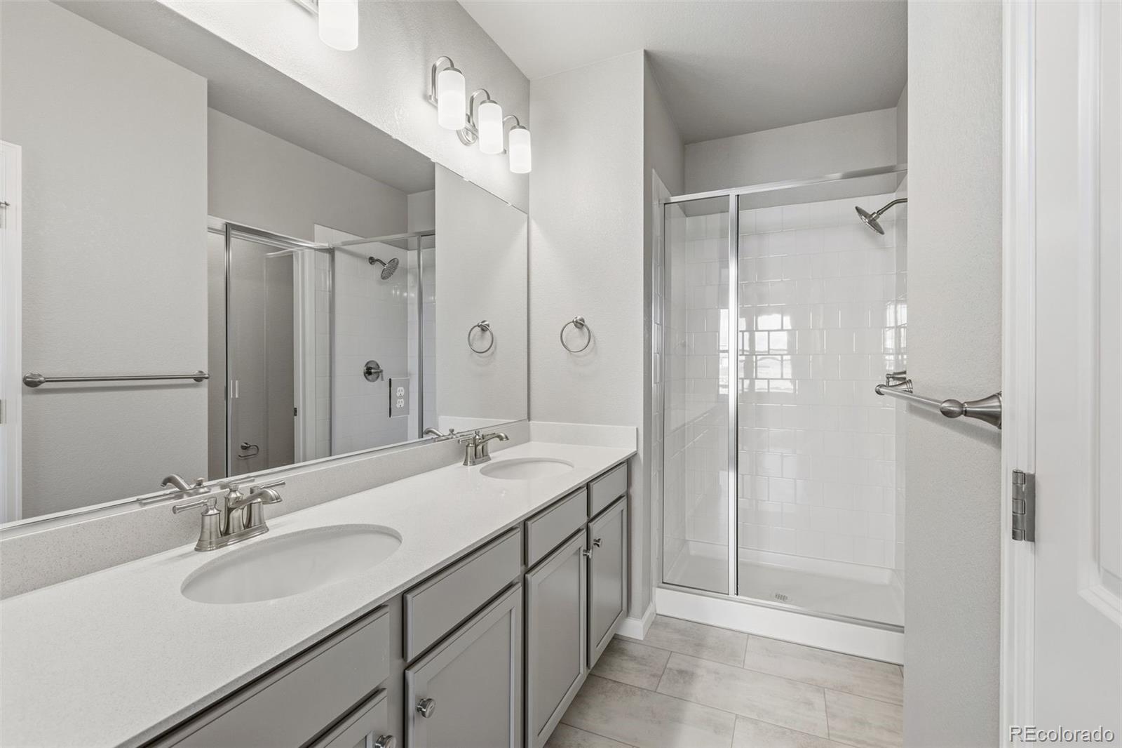 6801 Utica Court Firestone, CO 80504 - Photo 14 of 22 a bathroom with a double vanity sink mirror and shower