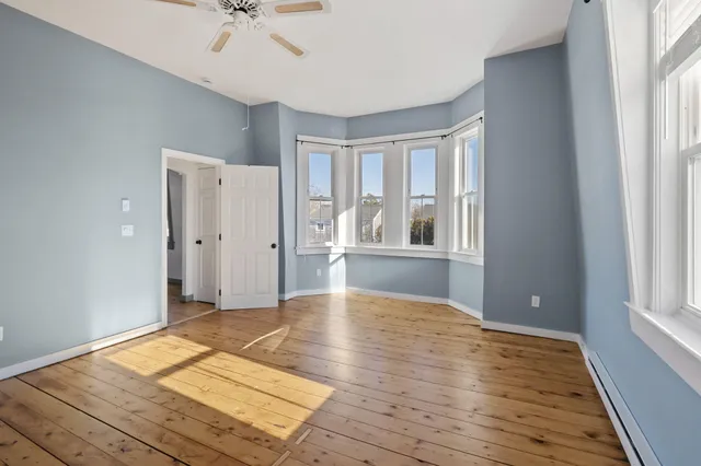 a view of an empty room with window and wooden floor