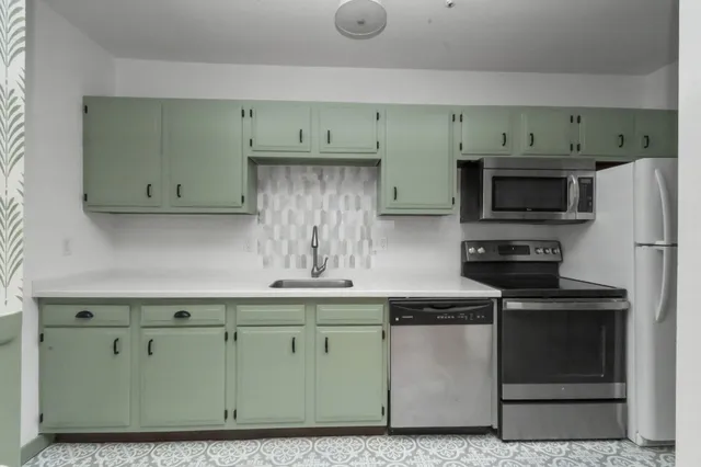 a kitchen with stainless steel appliances granite countertop a stove a sink and a microwave