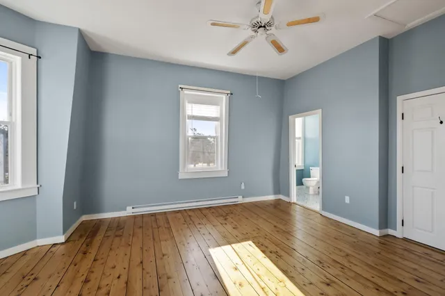 a view of empty room with wooden floor and fan
