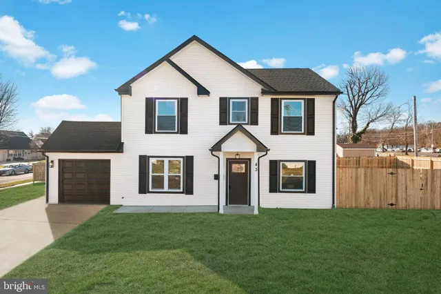 a view of a yard in front of a house with plants and large tree