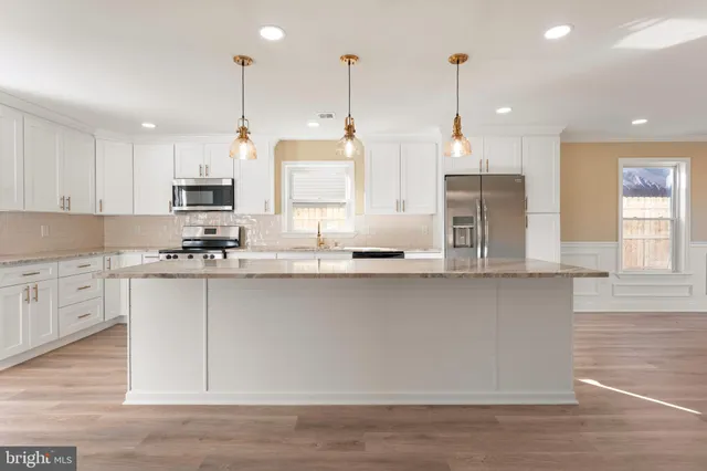 a kitchen with stainless steel appliances granite countertop a sink a stove a refrigerator a center island and cabinets