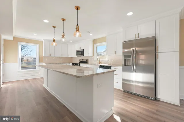 a kitchen with kitchen island a counter top space cabinets and stainless steel appliances