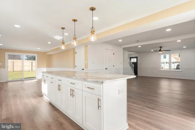 a large kitchen with granite countertop a large kitchen island and a sink dishwasher refrigerator with wooden floor