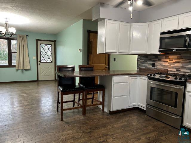 8353 Mannik Road Iron River, WI 54847 - Photo 30 of 52 Kitchen with a breakfast bar, appliances with stainless steel finishes, white cabinets, tasteful backsplash, and a textured ceiling