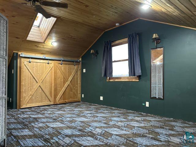 8353 Mannik Road Iron River, WI 54847 - Photo 41 of 52 Bonus room with wood ceiling, vaulted ceiling, a skylight, ceiling fan, and a barn door