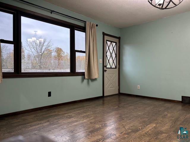 8353 Mannik Road Iron River, WI 54847 - Photo 44 of 52 Empty room with dark wood-style floors, a chandelier, and a textured ceiling