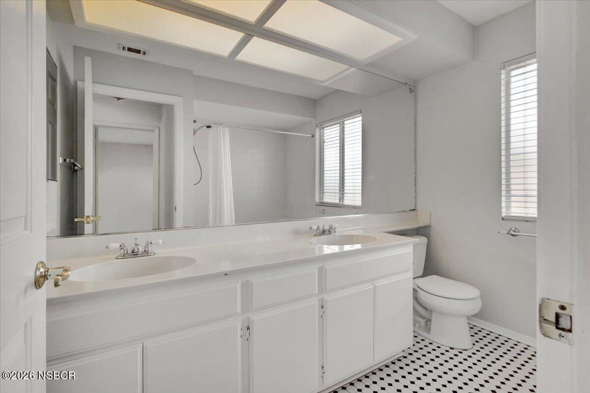 1248 Stonebrook Drive Lompoc, CA 93436 - Photo 27 of 38 a bathroom with a toilet a sink a mirror a window and vanity
