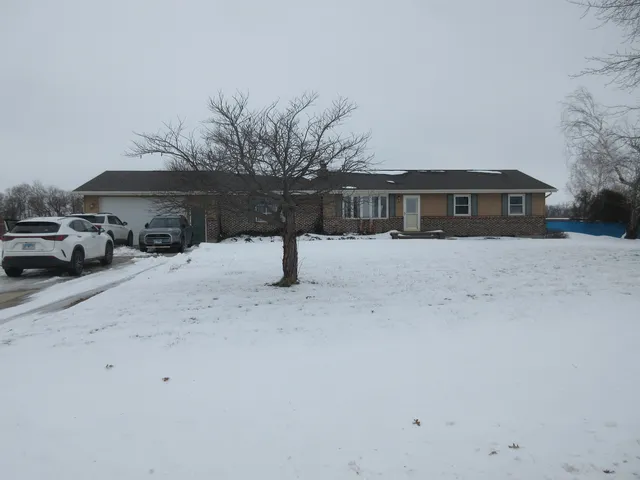 a front view of a house with a yard covered in snow