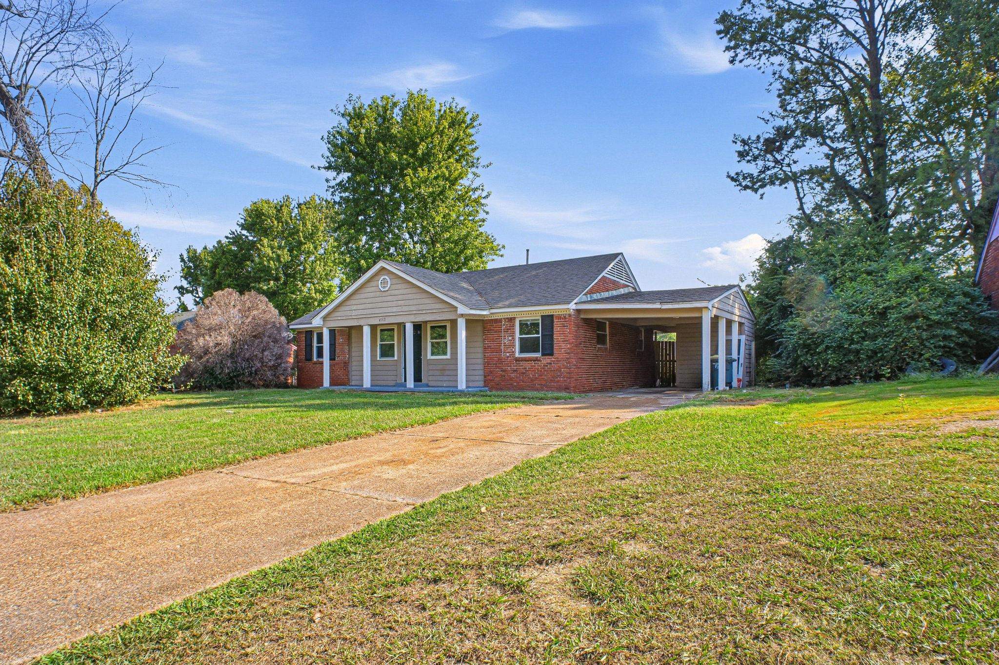 4562 Tulane Road Memphis, TN 38109 - Photo 2 of 32 Brick and siding exterior with a covered carport, mature trees, and a concrete driveway