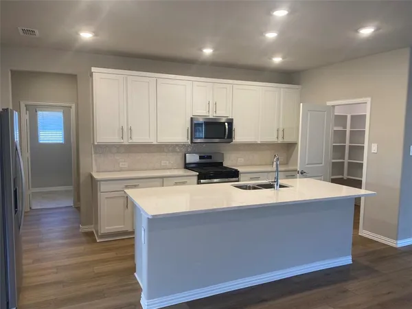 a kitchen with kitchen island granite countertop a sink and a stove top oven