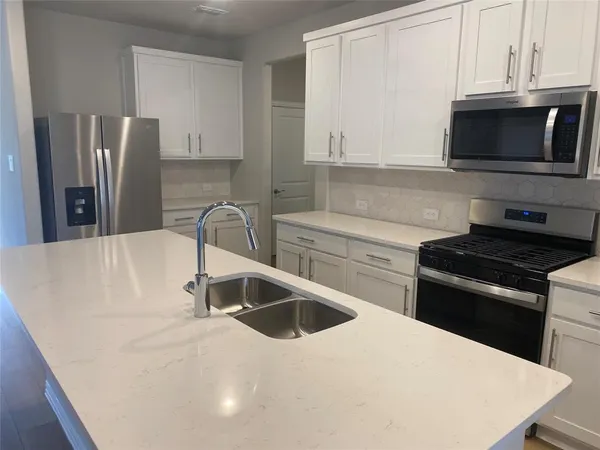 a kitchen with stainless steel appliances a sink a stove a microwave a sink a refrigerator and cabinets