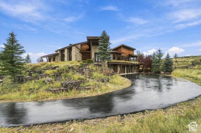 5936 Triple Crown Trail Oakley, UT 84055 - Photo 57 of 57 Stone and wood-clad exterior with multiple architectural levels, natural landscaping, an expansive paved driveway, and mature evergreen trees