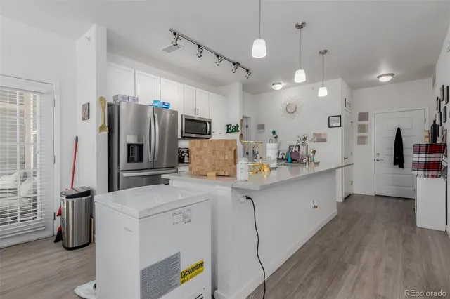 a kitchen with a sink stainless steel appliances cabinets and wooden floor