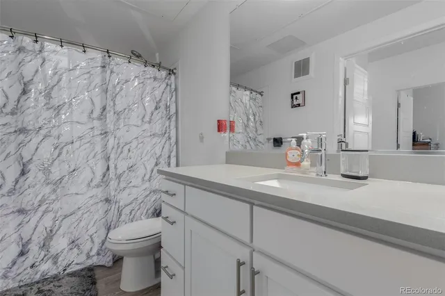 a bathroom with a granite countertop sink and a toilet
