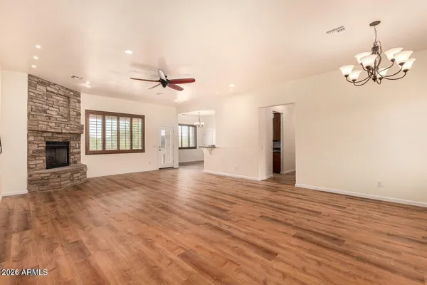 a view of an empty room with wooden floor and a fireplace