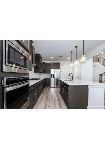 a kitchen with stainless steel appliances kitchen island granite countertop a stove a sink and a microwave