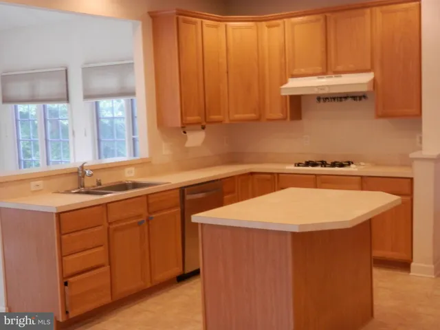 a kitchen with stainless steel appliances granite countertop a refrigerator a sink and a stove with wooden floor