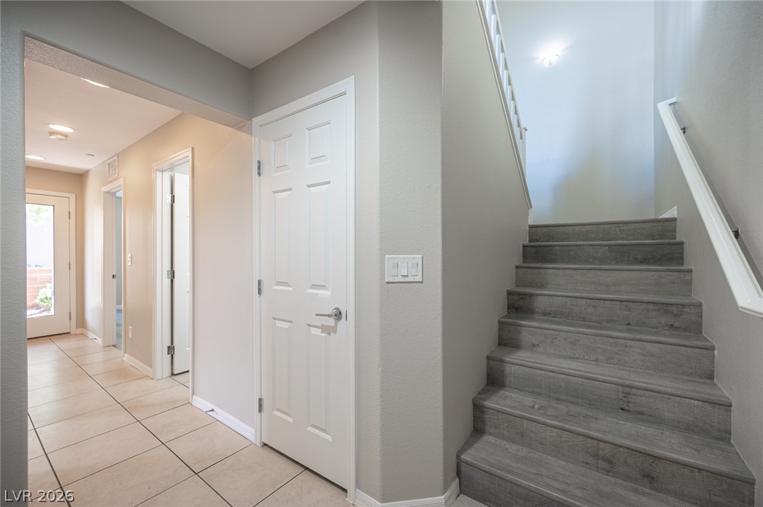 9916 Sable Point Street Las Vegas, NV 89178 - Photo 14 of 73 A well-lit entryway features a sleek staircase and tiled flooring.