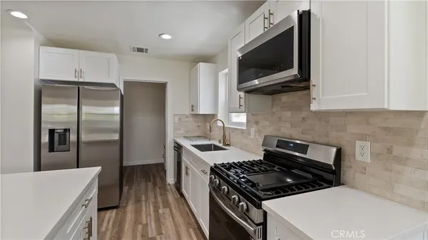 a kitchen with stainless steel appliances a refrigerator a stove top oven a sink and dishwasher