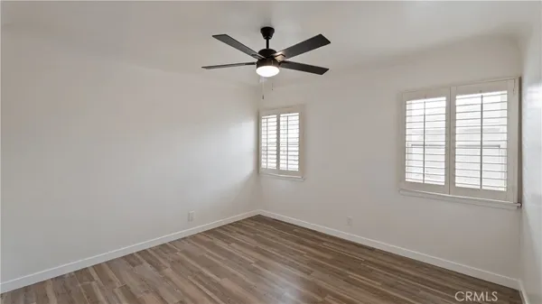 an empty room with wooden floor fan and windows