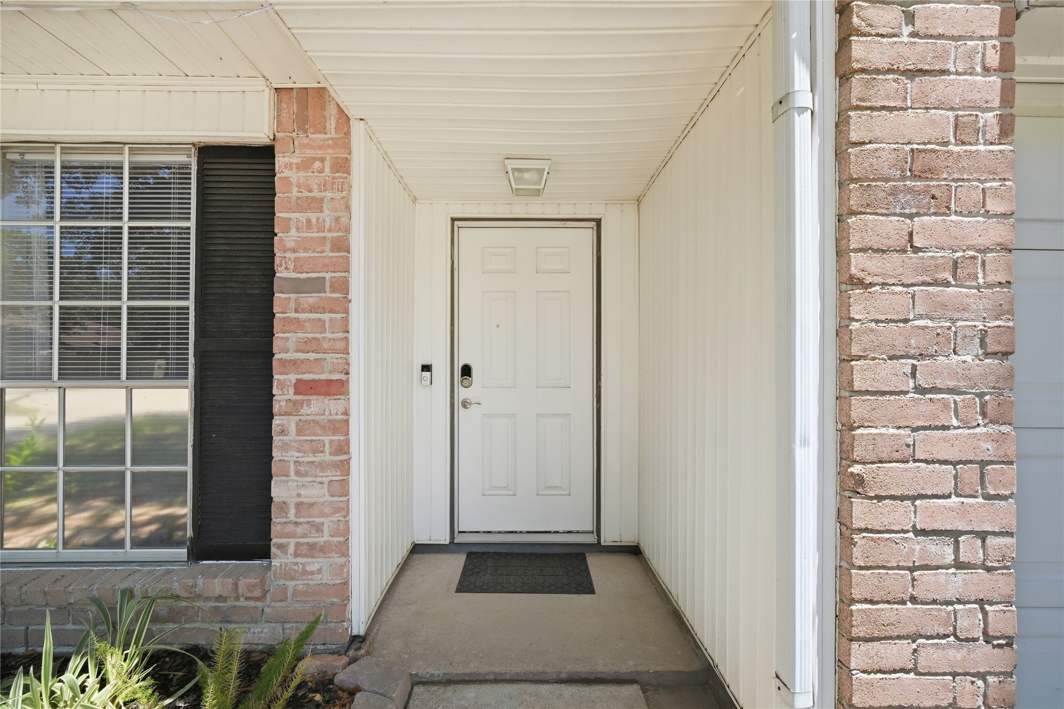 4718 Temple Bell Drive Spring, TX 77388 - Photo 5 of 50 This photo shows a welcoming front entrance with a white door, framed by brick and siding. A large window with black shutters and some greenery adds charm to the entryway.