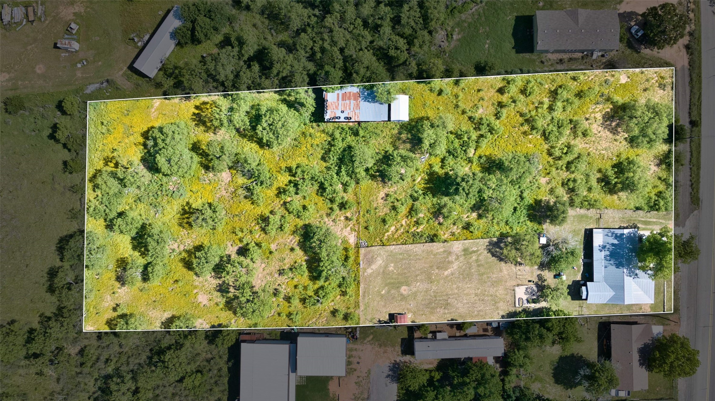 904 Bluebonnet Road Mason, TX 76856 - Photo 27 of 28 Expansive lot featuring a single-story residence with a light-colored roof, multiple outbuildings, and a mix of cleared and treed areas