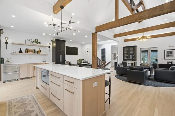 a large kitchen with kitchen island a stove a sink a dining table and chairs with wooden floor
