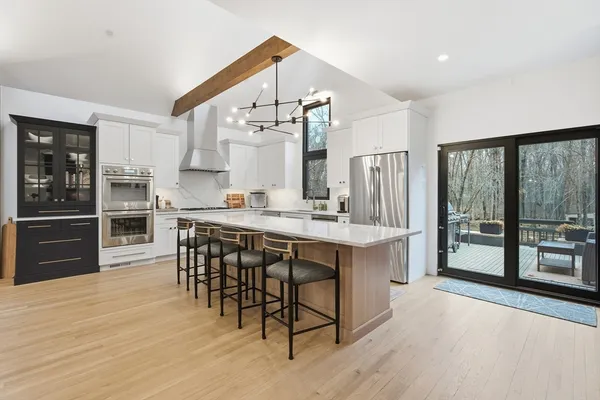 a kitchen with stainless steel appliances kitchen island granite countertop a table chairs sink and cabinets