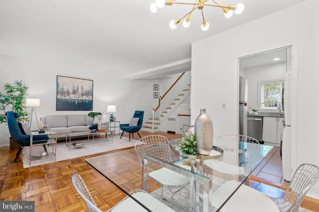 a living room with furniture kitchen view and a chandelier