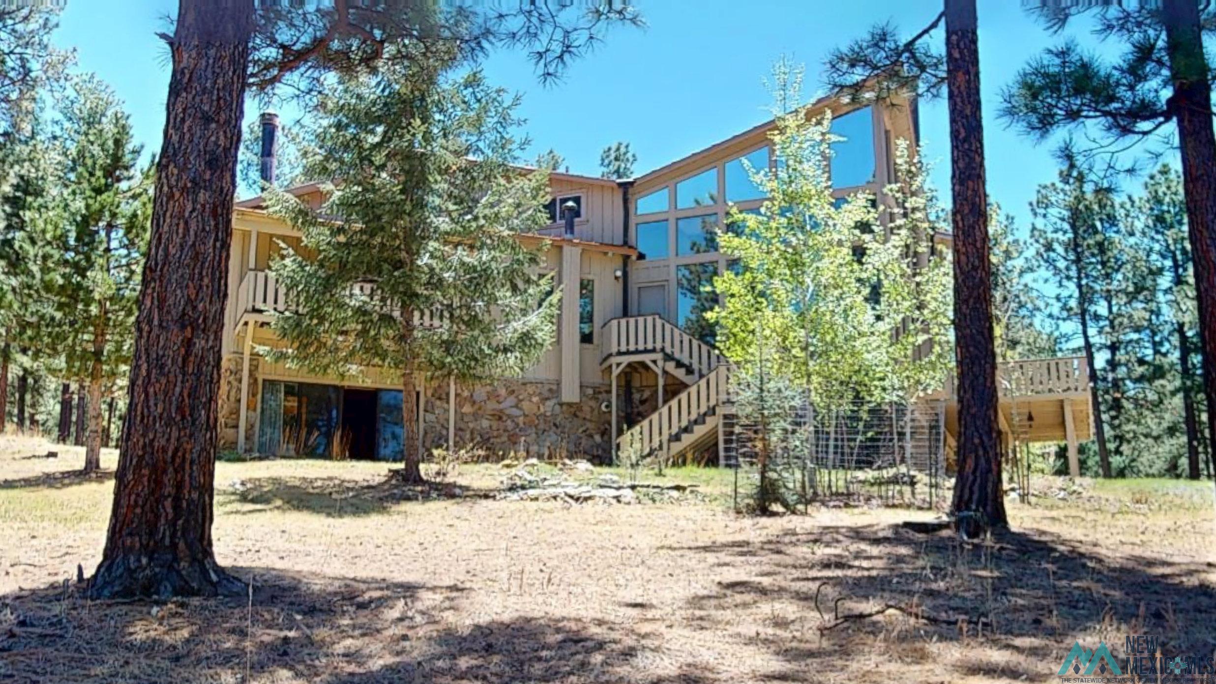 39 Alta Vista Rociada, NM 87742 - Photo 51 of 54 Contemporary architectural style featuring extensive glass panels, multiple outdoor balconies, stone and wood siding, and an exterior staircase