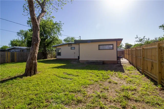 a view of backyard with wooden fence and a large tree