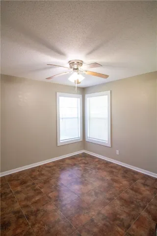 en empty room with windows and chandelier fan