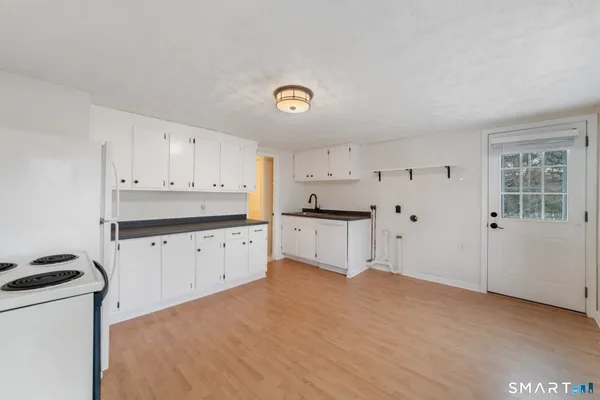 a kitchen with granite countertop a stove a sink dishwasher and a refrigerator with wooden floor