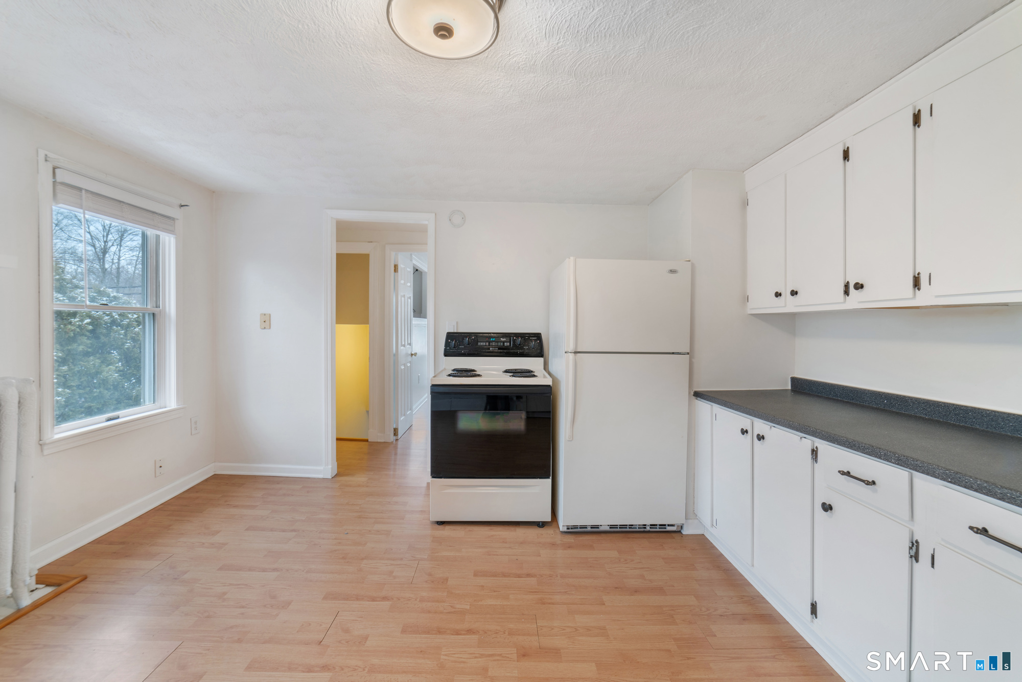 25 High Street Windsor, CT 06095 - Photo 24 of 40 a kitchen with granite countertop white cabinets and refrigerator