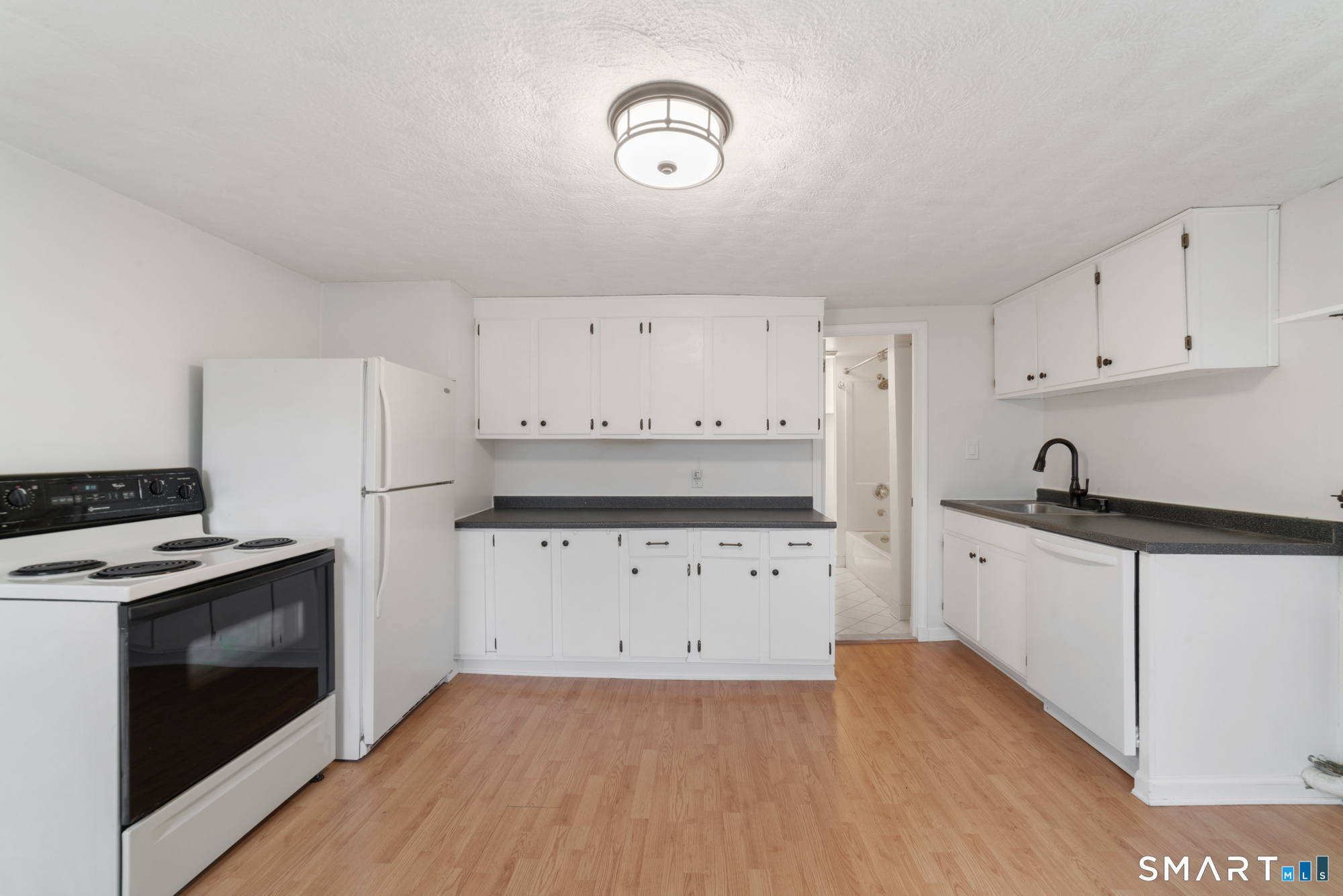 25 High Street Windsor, CT 06095 - Photo 26 of 40 a kitchen with granite countertop white cabinets and white appliances