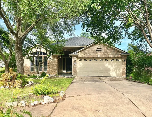 a front view of a house with a garden and trees