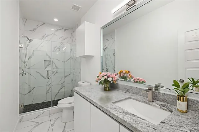 a bathroom with a granite countertop sink a toilet and shower