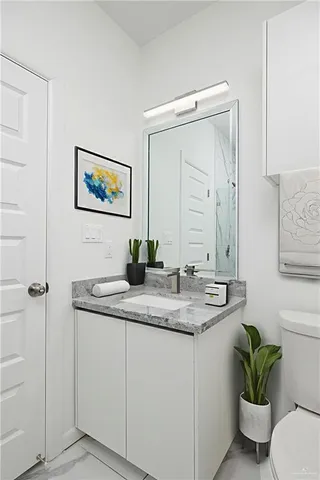 a bathroom with a granite countertop sink a toilet and a mirror