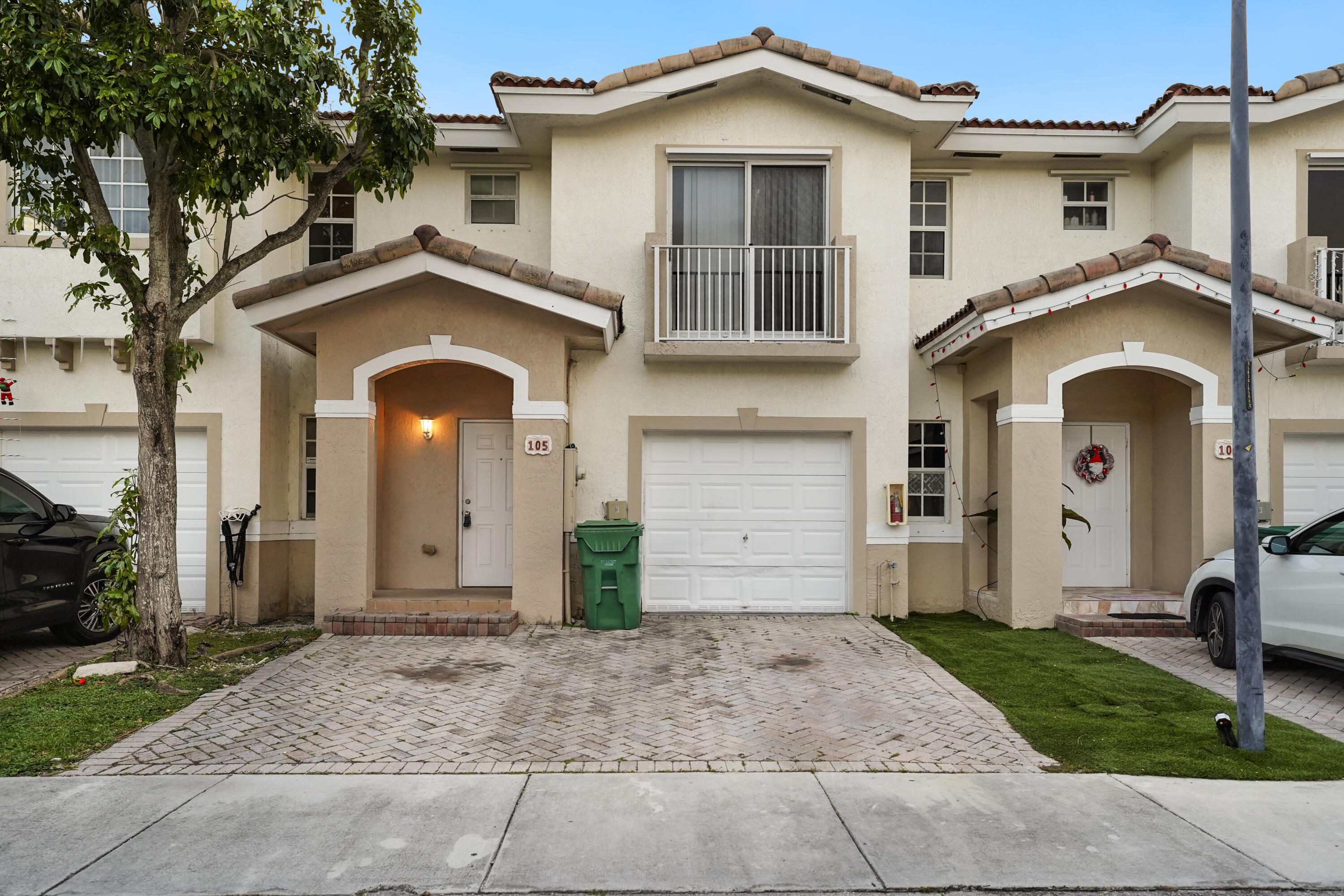 14142 Southwest 260th Street, Unit 105 Homestead, FL 33032 - Photo 1 of 17 a front view of a house with a yard and garage