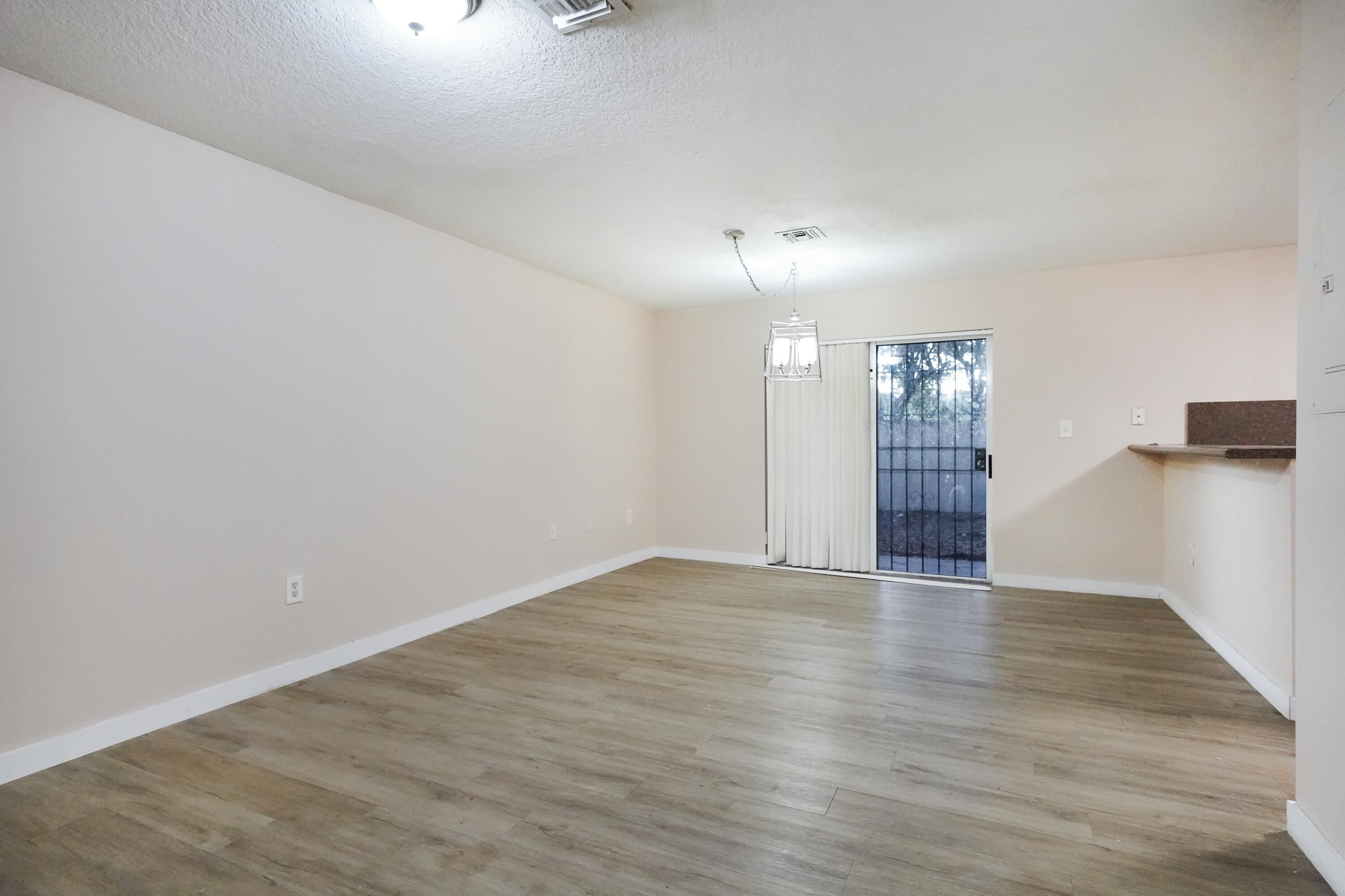 14142 Southwest 260th Street, Unit 105 Homestead, FL 33032 - Photo 3 of 17 wooden floor in an empty room with a window