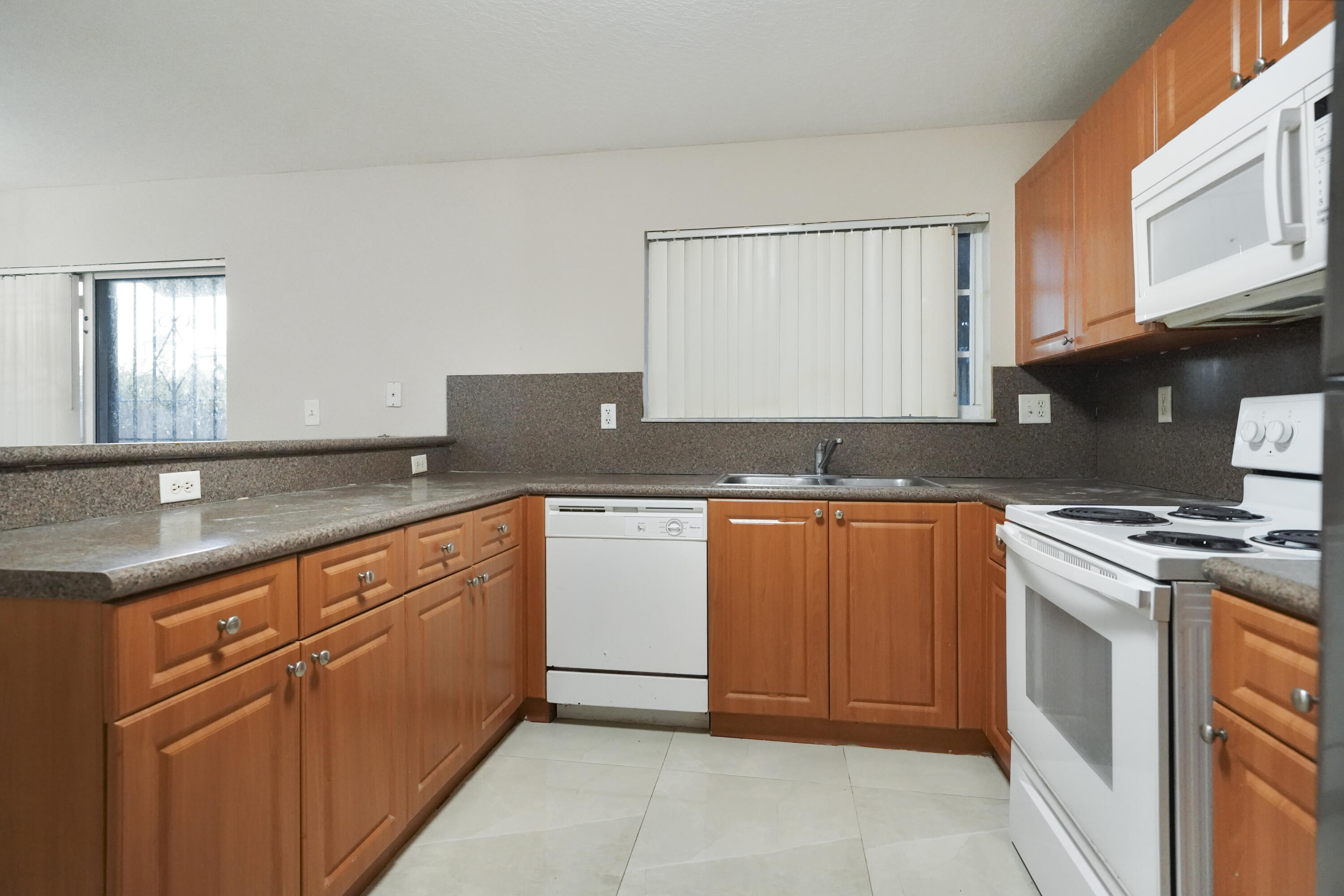 14142 Southwest 260th Street, Unit 105 Homestead, FL 33032 - Photo 5 of 17 a kitchen with granite countertop a sink and a stove