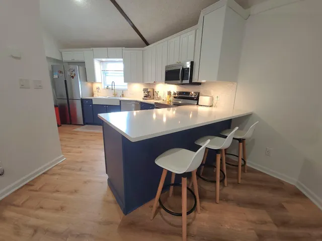 a kitchen with stainless steel appliances granite countertop a sink a stove a refrigerator cabinets and chairs