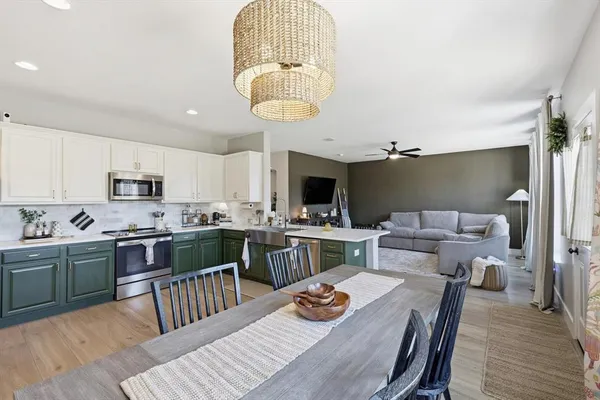 a kitchen with a table chairs a sink dishwasher stove and cabinets with wooden floor