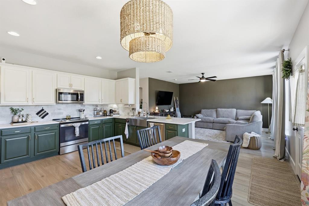 a kitchen with a table chairs a sink dishwasher stove and cabinets with wooden floor