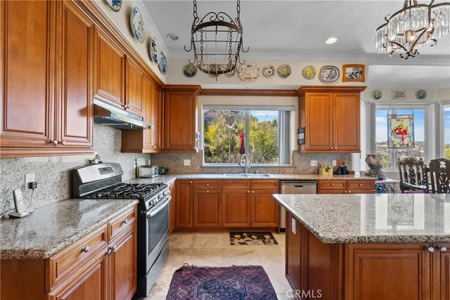 a kitchen with stainless steel appliances granite countertop a sink a stove top oven a counter space and cabinets