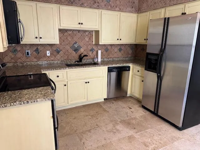 a kitchen with granite countertop a refrigerator sink and white cabinets