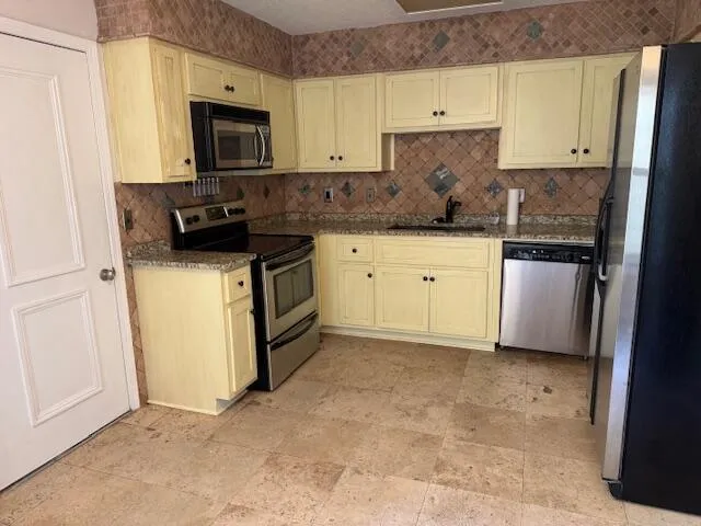 a kitchen with stainless steel appliances granite countertop a stove a sink and a refrigerator